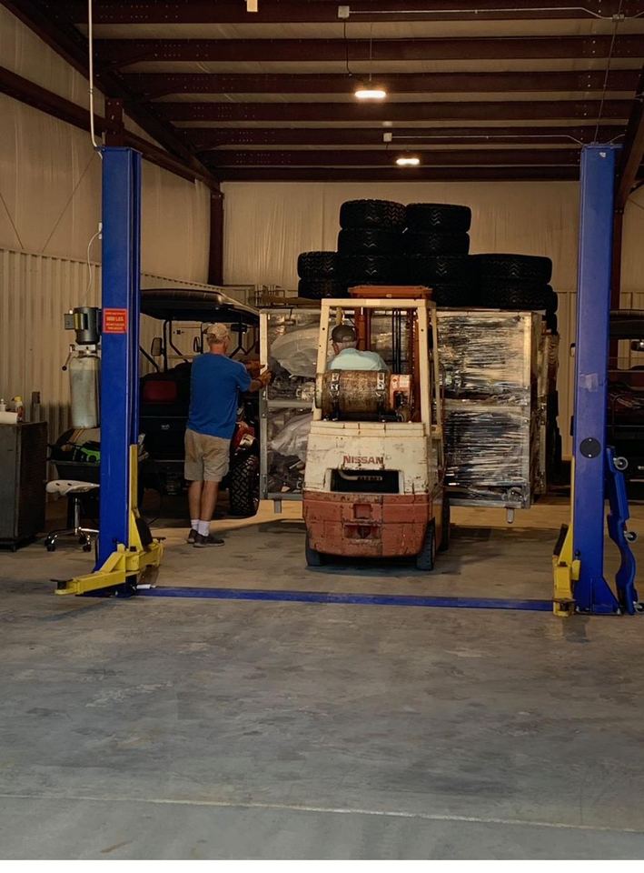 Inside the Tuscaloosa Custom Carts service shop — lift, tires, and builds in progress